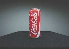 A classic Coca-Cola can showcased on a dark surface with minimal lighting.